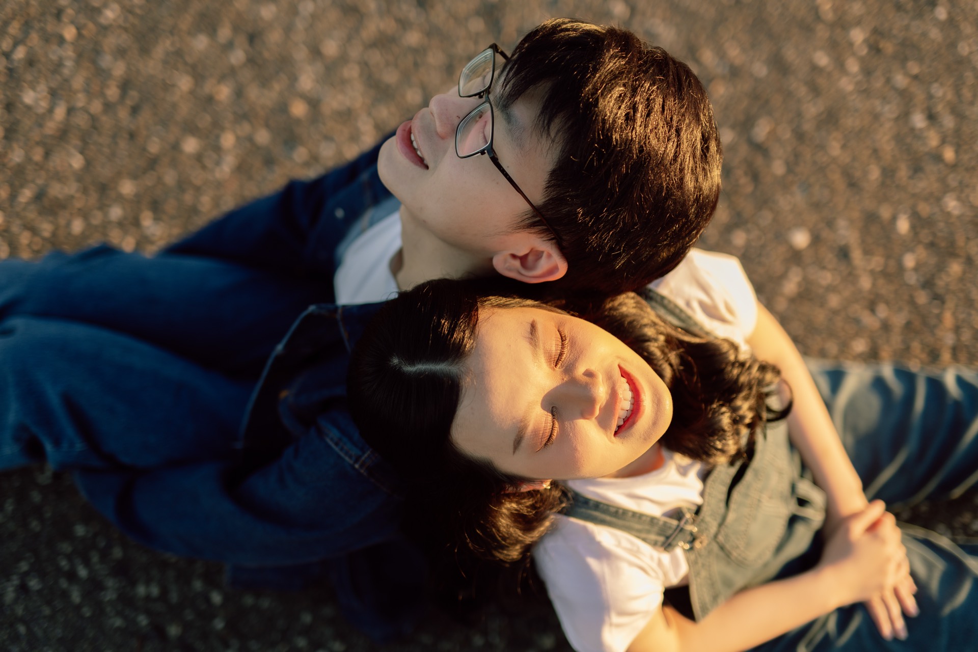 Rey and Feli lying close together on a quiet road in the afternoon light