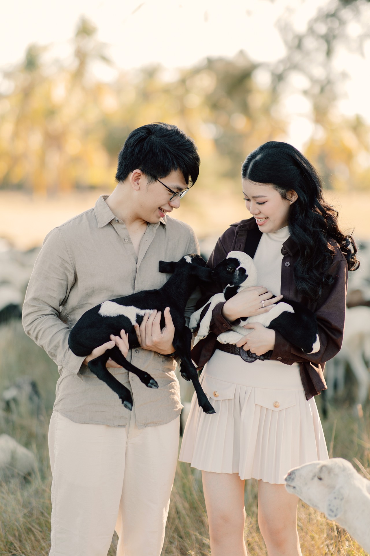 Rey and Feli smiling together while each holds a small lamb