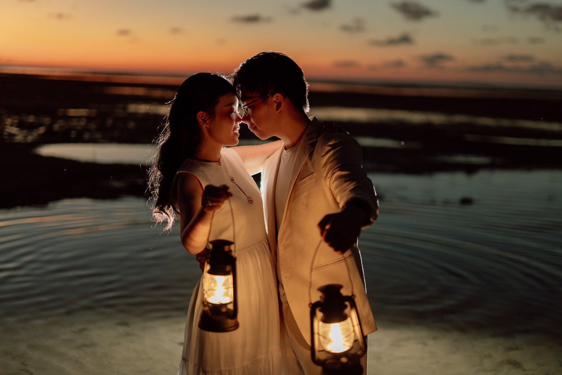 Rey and Feli holding lanterns and touching foreheads after sunset