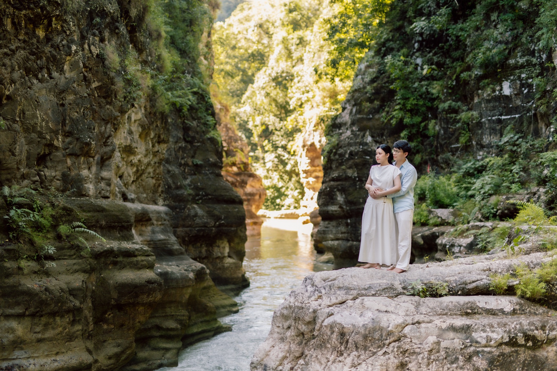 Rey and Feli standing together in a sunlit canyon surrounded by trees