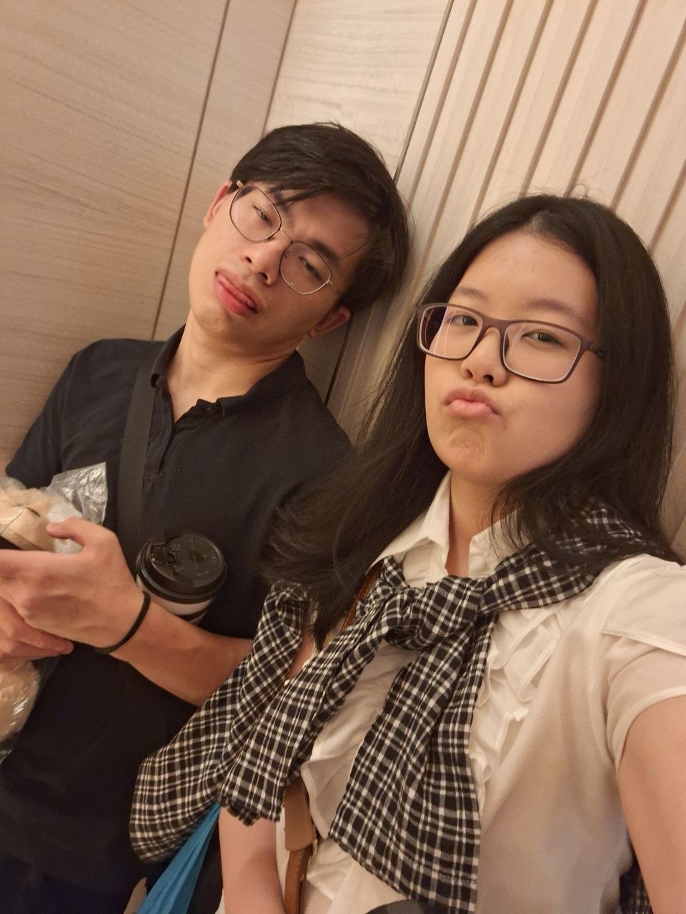 Rey and Feli taking a playful elevator selfie while wearing glasses